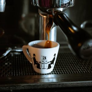 white and black ceramic mug on black and silver coffee maker