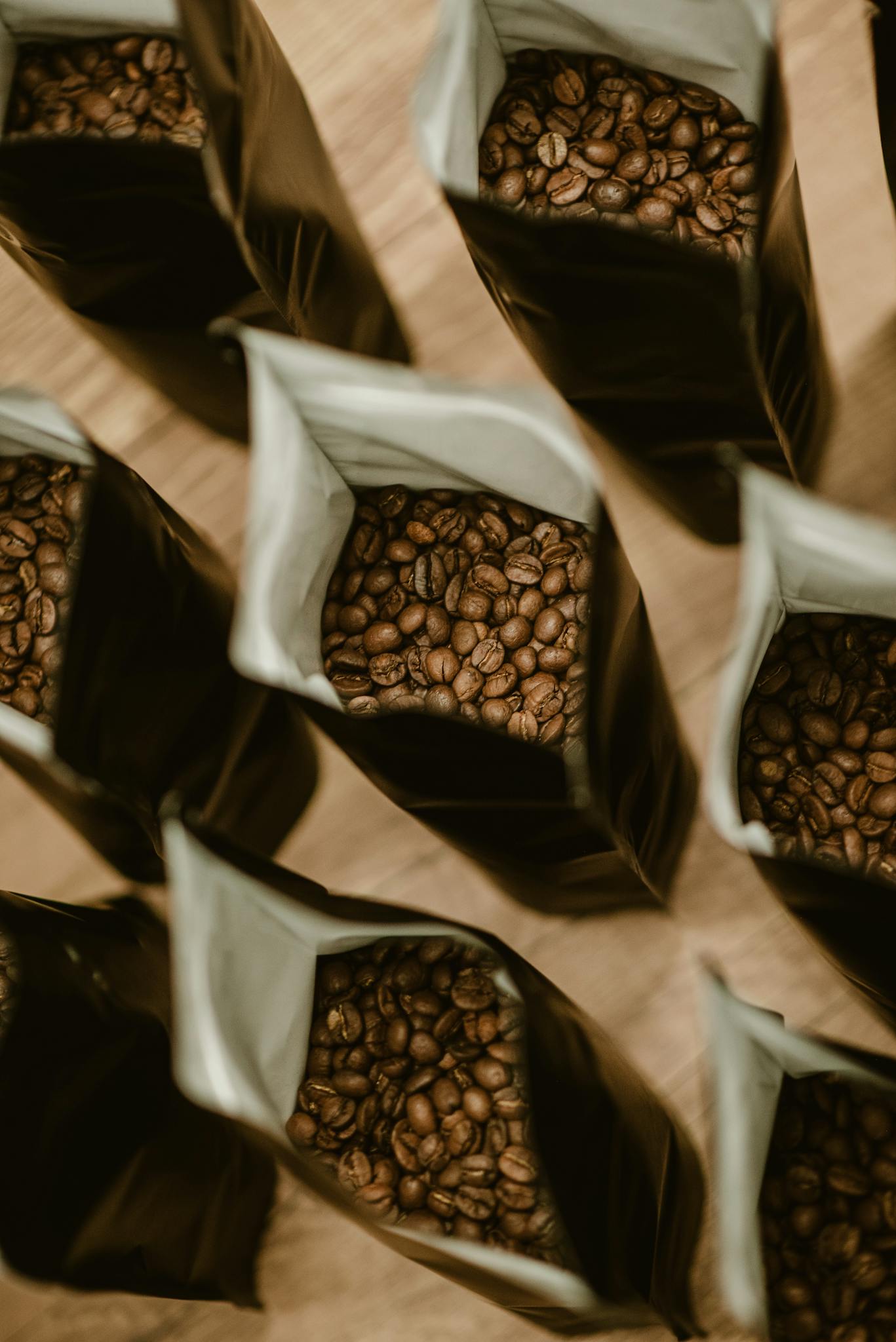Several bags filled with fresh coffee beans from a high angle view, showing abundance.